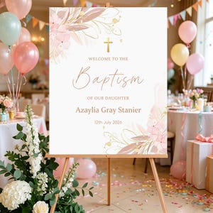 Puede incluir: Un letrero de bienvenida rectangular blanco para un bautizo con una cruz dorada, ilustraciones florales en tonos rosa y beige, y el texto: Welcome to the Baptism of our daughter, Azaylia Gray Stanier, 12th July 2026, sobre un caballete.