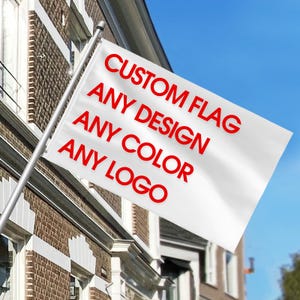May include: A white rectangular flag attached to a silver metal pole. The flag features bold red text that reads: CUSTOM FLAG, ANY DESIGN, ANY COLOR, ANY LOGO. The flag is positioned at an angle against a clear blue sky and a brick building.