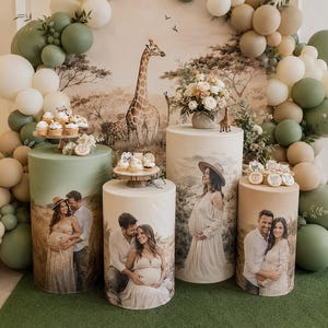 Può includere: Un set di quattro piedistalli cilindrici con fotografie stampate di una coppia, disposti con archi di palloncini nei toni del verde salvia, crema e marrone chiaro. L'allestimento include cupcake, biscotti e uno sfondo a tema giraffa.