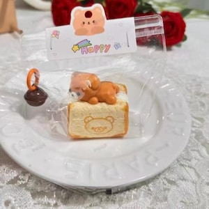 May include: A white ceramic mug with a black handle and the text "But First, Coffee" in a black, handwritten-style font. The mug is on a white surface.