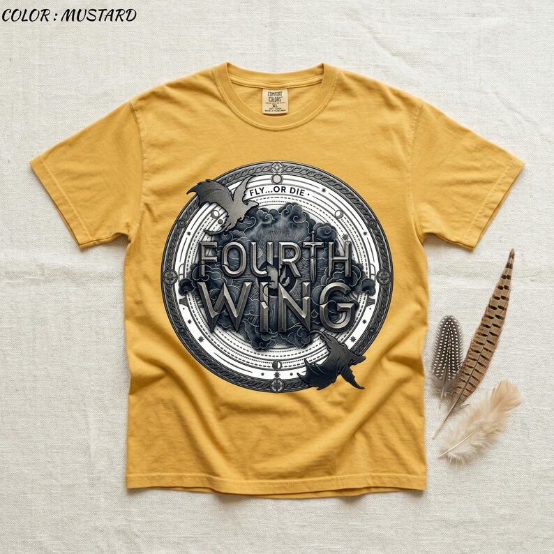 May include: Mustard-colored t-shirt featuring a circular graphic with the words "FOURTH WING" in a stylized font. The graphic includes two stylized bat-like creatures and the phrase "FLY...OR DIE". The shirt has short sleeves and a crew neck.