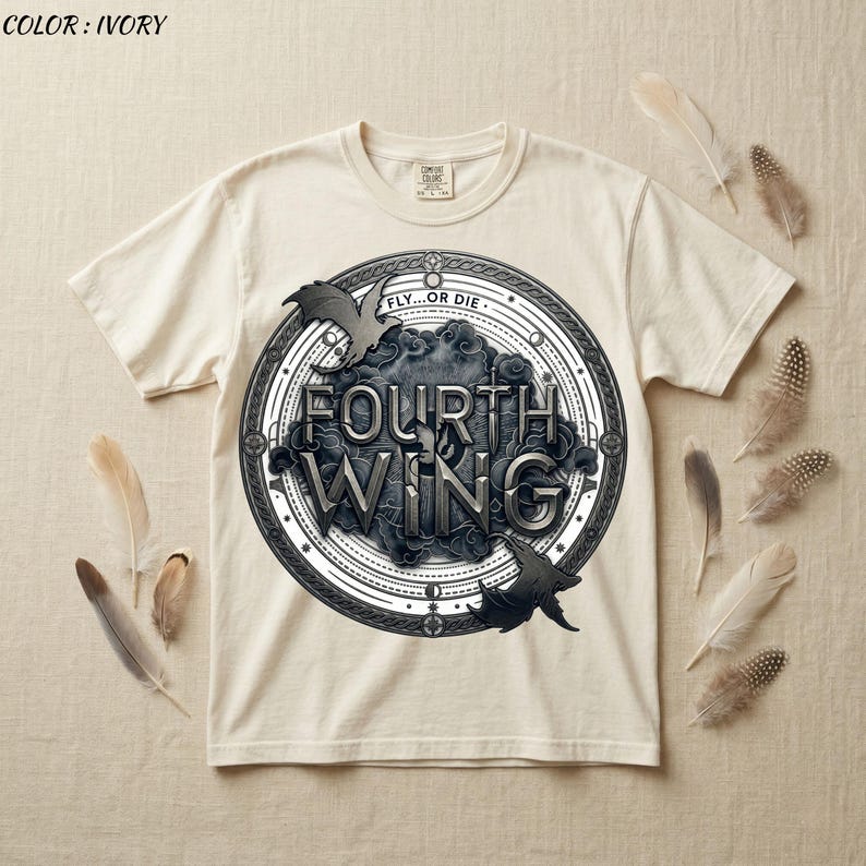 May include: Ivory-colored t-shirt featuring a circular graphic with the words "FOURTH WING" in a stylized font. The design includes bat silhouettes and the phrase "FLY...OR DIE". Feathers are arranged around the shirt.