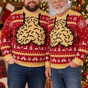 May include: A red and tan long-sleeve knit jumper featuring a large, central graphic of two tan, brain-like shapes suspended by black lines. The jumper includes a festive pattern of white snowflakes, reindeer, Christmas trees, and gift boxes.