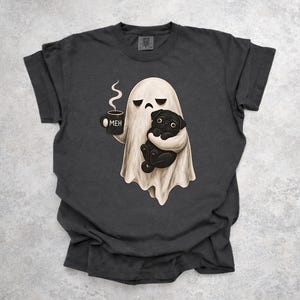 Peut inclure: Un t-shirt gris anthracite avec un motif représentant un fantôme blanc tenant une tasse noire sur laquelle est inscrit le mot MEH. Le fantôme tient également un petit carlin noir. Le motif est centré sur le devant du t-shirt à manches courtes.