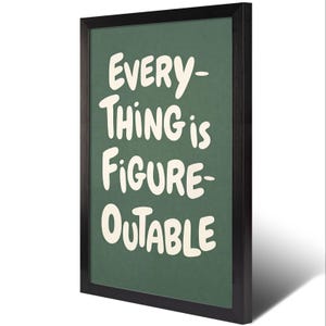 May include: A framed print with the words "EVERYTHING is FIGURE-OUTABLE" in white, bold, handwritten-style font on a dark green background. The frame is black. The print is angled slightly, casting a shadow.