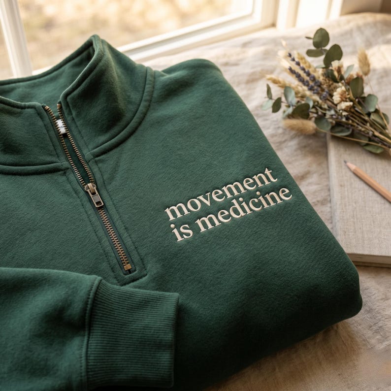 K&ouml;nnte beinhalten: Dunkelgr&uuml;nes Sweatshirt mit einem Viertel-Rei&szlig;verschluss und dem gestickten Text "movement is medicine" in Wei&szlig;. Das Sweatshirt besteht aus einem weichen Material und ist f&uuml;r den Freizeitgebrauch geeignet.