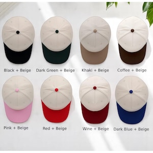 May include: Eight baseball caps arranged in two rows, each featuring a beige crown and a colored brim. The caps have a small button on top matching the brim color. The color combinations are labeled: Black + Beige, Dark Green + Beige, Khaki + Beige, Coffee + Beige, Pink + Beige, Red + Beige, Wine + Beige, and Dark Blue + Beige.