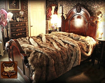 May include: A brown faux fur throw blanket on a wooden bed frame with a carved headboard. The bed is in a room with dark wallpaper and a vintage dresser.