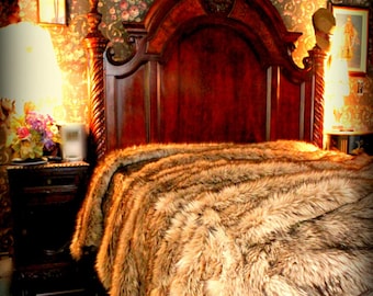 May include: A luxurious faux fur throw blanket in shades of brown and beige, draped over a wooden bed frame with a carved headboard. The blanket has a soft, fluffy texture and is perfect for adding warmth and style to any bedroom.