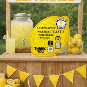 Op de afbeelding: Een limonadekraam met een houten structuur, met een bord met de tekst "LEMONADE". Een geel, citroenvormig bord toont "BRAAAP FUEL" en menu-items. Verse citroenen en glazen limonade zijn zichtbaar.