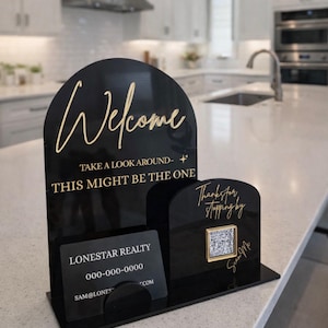 May include: Black acrylic welcome sign with gold lettering. The sign reads "Welcome, Take a look around - This might be the one." Includes a business card holder and a QR code. The business card reads "Lonestar Realty".