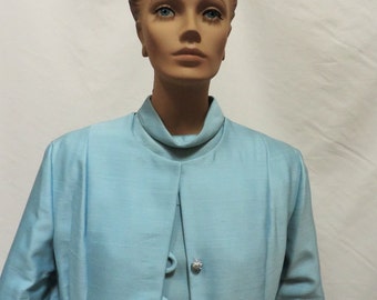 May include: A light blue blazer with a high collar and four decorative buttons. The blazer has long sleeves and a fitted silhouette.