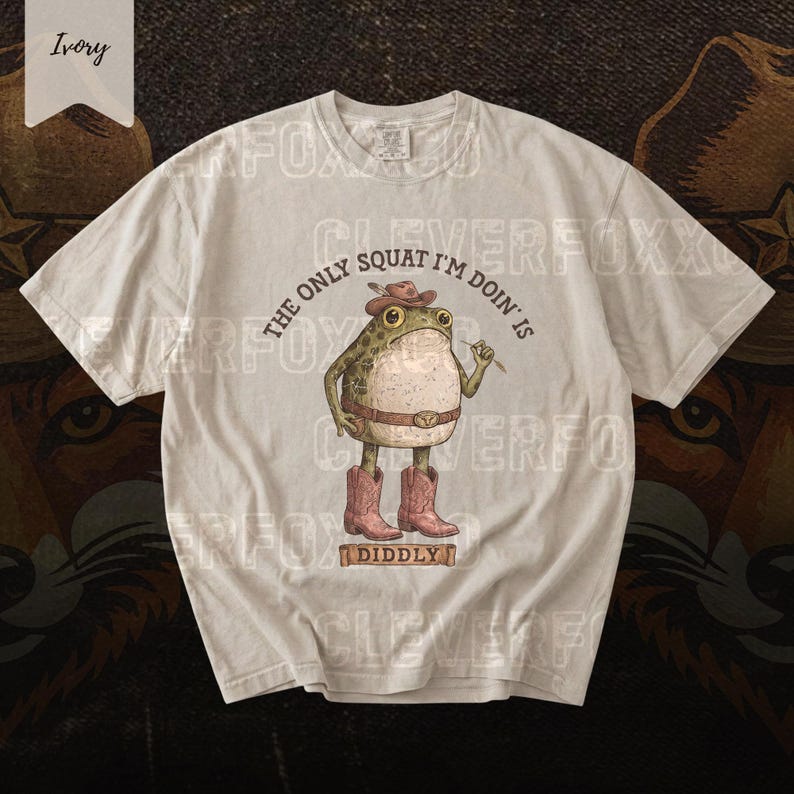 A white t-shirt with a cartoon frog wearing cowboy boots and a hat, along with the text "The only squat I'm done is" and "Diddyly" printed on it.