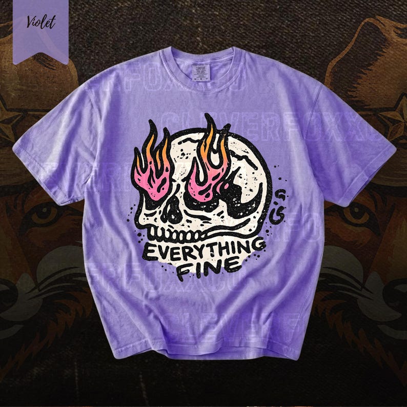 Puede incluir: Camiseta violeta con un dise&ntilde;o gr&aacute;fico de calavera con llamas rosas y naranjas. El texto "EVERYTHING FINE" est&aacute; debajo. La camiseta tiene mangas cortas y cuello redondo.