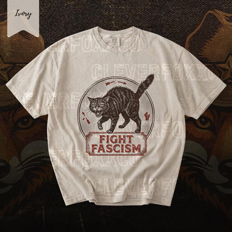 A white t-shirt with a graphic design featuring a cat and the text "FIGHT FASCISM" printed on it.