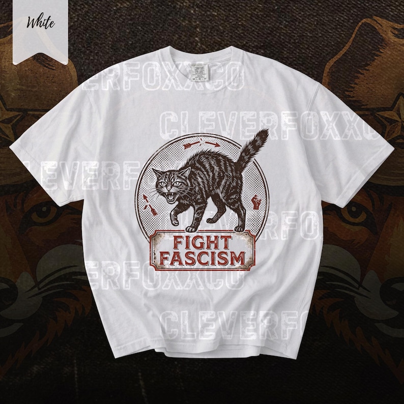 A white t-shirt with a graphic design featuring a cat and the text "FIGHT FASCISM" printed on it.