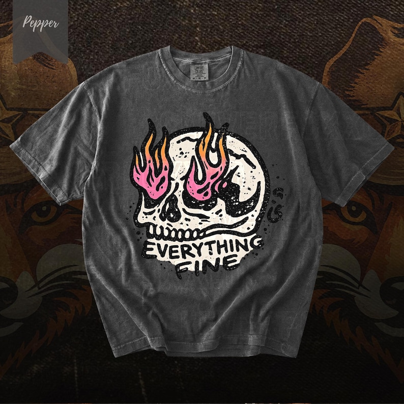 Puede incluir: Camiseta gris oscuro con un dise&ntilde;o de calavera y llamas rosas y naranjas. El texto "EVERYTHING FINE" est&aacute; debajo de la calavera. La camiseta tiene un aspecto vintage y desgastado.