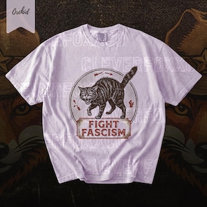A white t-shirt with a graphic design featuring a cat and the text "FIGHT FASCISM" printed on it.