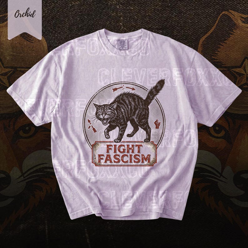 A white t-shirt with a graphic design featuring a cat and the text "FIGHT FASCISM" printed on it.