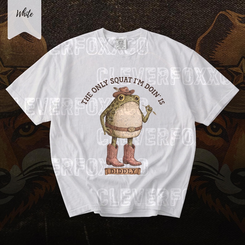 A white t-shirt with a graphic design featuring a frog character wearing cowboy boots and holding a cigarette.