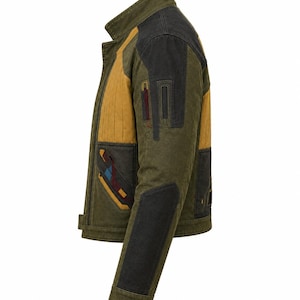 May include: A side view of an olive green jacket featuring mustard yellow panels on the chest and back, black shoulder and elbow patches, and decorative geometric accents in maroon and blue on the front pocket and sleeve areas.