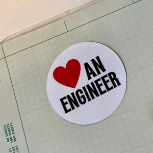 May include: A white circle sticker with a red heart and the text "I AN ENGINEER" in black.