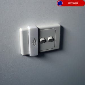 May include: A white electrical outlet cover with a wireless symbol is attached to a light switch on a grey wall. The light switch has two round buttons. The image is a close-up shot.
