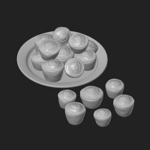 Könnte beinhalten: Eine Ansammlung kleiner, runder, grauer Objekte, möglicherweise Muffins oder Cupcakes, ist auf einem weißen Teller angeordnet und darum herum verstreut. Die Objekte haben eine abgerundete Oberseite mit einer leichten Vertiefung. Der Hintergrund ist einfarbig schwarz.