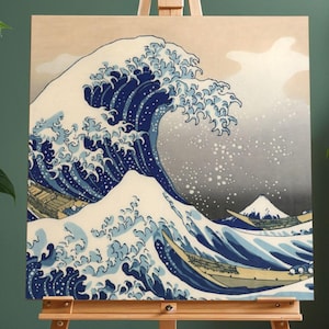 以下が含まれることがあります： 浮世絵師、葛飾北斎の「神奈川沖浪裏」のプリントがイーゼルに飾られています。青と白を基調とした大きな波が描かれ、背景には富士山、波の谷間には小舟が描かれています。