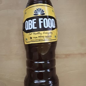 May include: A brown plastic bottle with a blue cap, labeled "OBE FOOD." The label is yellow with black text and a lotus flower design. The bottle contains a dark liquid and has a ribbed design.