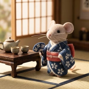 Könnte beinhalten: Eine Filz-Maus-Figur in einem blauen Kimono mit weißen Blumenmustern und einem roten Obi. Die Maus hält einen Fächer und steht in der Nähe eines kleinen Holztisches mit einer Teekanne und Tassen, vor einem traditionellen japanischen Hintergrund.