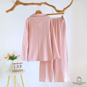 Może przedstawiać: Biały ceramiczny kubek z czarnym uchwytem i napisem "But First, Coffee" czarną, odręczną czcionką. Kubek stoi na białej powierzchni.