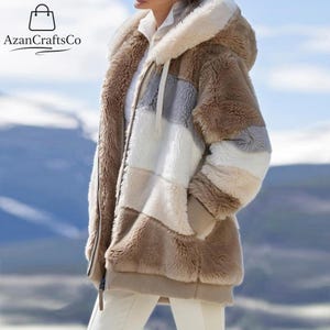 May include: A patchwork faux fur jacket in shades of brown, beige, grey, and white. The jacket has a full zip and a drawstring hood. The sleeves have a ribbed cuff. The jacket is designed for warmth and style, suitable for colder weather.