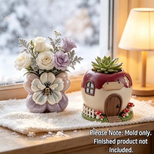 May include: A ceramic flower-shaped vase with a bee motif containing white and purple roses, alongside a round house-shaped planter with a succulent, a brown door, a white fence, and red mushrooms. Text reads: Please Note: Mold only. Finished product not included.