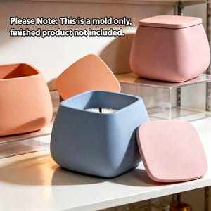 May include: A set of square silicone molds for containers with rounded corners, including one light blue mold with a candle inside, one peach mold, and one pink mold with a matching lid. Text reads: Please Note: This is a mold only, finished product not included.