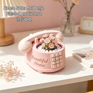 May include: A light pink silicone mold shaped like a vintage rotary telephone with a handset on top and a keypad on the side. The text "Beautiful Home" is embossed on the front. The mold is empty, and the text "Please Note: Mold only. Finished product not included" is visible.
