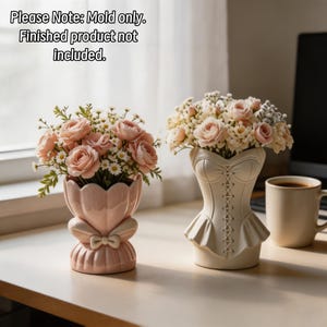 May include: Two silicone molds for vases, one shaped like a scalloped bowl with a bow and the other like a corset with lace-up detail. Text reads: Please Note: Mold only. Finished product not included. The molds are light pink and off-white.