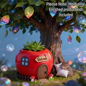 May include: A silicone mold for a red apple-shaped house planter featuring a small door, a window, a fence, and a sign that reads "Welcome". The text "Please Note: Mold only. Finished product not included." is visible at the top of the image.