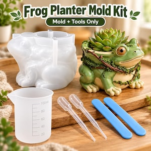 May include: A Frog Planter Mold Kit featuring a translucent silicone frog-shaped mold, a finished green frog planter with a succulent, a 100ml measuring cup, two clear plastic droppers, and two blue stirring sticks for crafting.