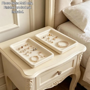 May include: Two rectangular off-white silicone trays with raised edges. The trays contain various small jewelry pieces, including pearl bracelets and stud earrings. Text on the image reads: Please Note: Mold only. Finished product not included.