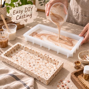 May include: A rectangular silicone mold being filled with a swirling beige and white liquid mixture. In the foreground, a finished rectangular tray features a speckled terrazzo pattern in shades of tan, brown, and white. Text reads Easy DIY Casting.