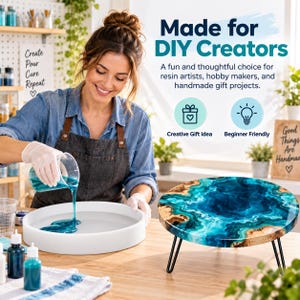 May include: A white circular silicone mold for resin casting, with a person pouring blue liquid resin into it. Beside the mold sits a finished round wooden tray with a blue and teal marbled resin inlay, supported by three black metal hairpin legs.
