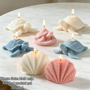 May include: A collection of seven wax candles shaped like sea turtles and seashells in white, blue, and pink. Each candle features a lit wick. The text at the bottom reads: Please Note: Mold only. Finished product not included.