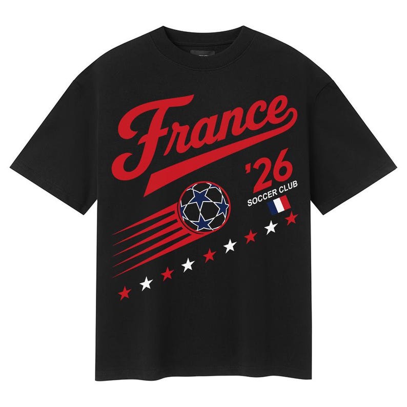 May include: Black t-shirt with a red script that says "France" above the text "'26 SOCCER CLUB". A soccer ball graphic with blue and white stars is in the center. Red and white stars and a French flag are also on the shirt.