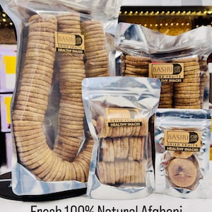 Może przedstawiać: Kilka przezroczystych plastikowych toreb wypełnionych suszonymi figami, oznaczonych jako "BASIRI DRIED FRUITS HEALTHY SNACKS". Figi są jasnobrązowe i ułożone w schludnych rzędach. Tekst na dole brzmi "Fresh 100% Natural Afghani Dried Figs (Anjeer)."