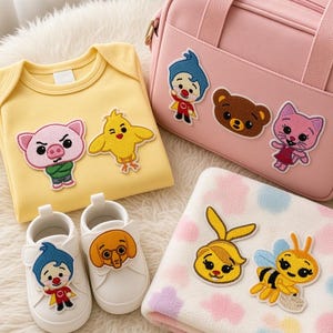 May include: A yellow bodysuit, a pink bag, white shoes, and a white blanket with pastel spots. The items feature embroidered patches of cartoon characters including a pig, chick, bear, cat, boy, dog, rabbit, and bee with yellow and black stripes.