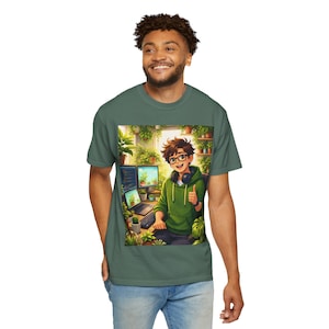 May include: Green t-shirt featuring a cartoon illustration of a person with glasses and headphones, giving a thumbs-up. The illustration shows the person in front of a computer surrounded by plants. The t-shirt is a solid green color.