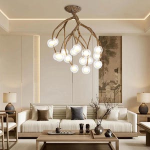 Könnte beinhalten: Eine moderne Deckenleuchte mit einem astähnlichen Design. Die Leuchte verfügt über mehrere klare Glaskugelleuchten, die an bronzefarbenen, strukturierten Ästen hängen. Die Deckenleuchte ist an einer strukturierten Deckenplatte befestigt.