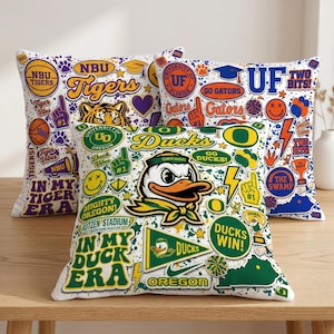Puede incluir: Tres cojines decorativos con fondo blanco y gr&aacute;ficos universitarios coloridos. Un coj&iacute;n presenta un tigre, el texto "Tigers" y las palabras "Tiger Vibes". Otro coj&iacute;n tiene una mascota de pato y el texto "Ducks". El tercer coj&iacute;n tiene el texto "Go Gators".