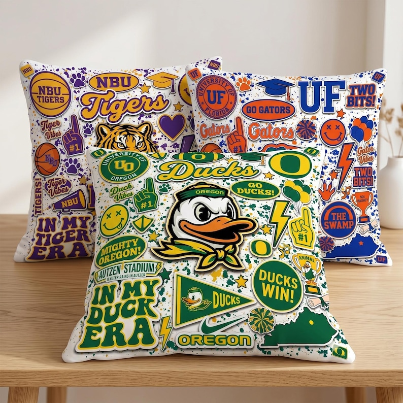 Puede incluir: Tres cojines decorativos con fondo blanco y gr&aacute;ficos universitarios coloridos. Un coj&iacute;n presenta un tigre, el texto "Tigers" y las palabras "Tiger Vibes". Otro coj&iacute;n tiene una mascota de pato y el texto "Ducks". El tercer coj&iacute;n tiene el texto "Go Gators".